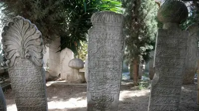 Akademisyenlerin tarihi mezar taşlarını fotoğraflayıp belgelediği bir sahne.