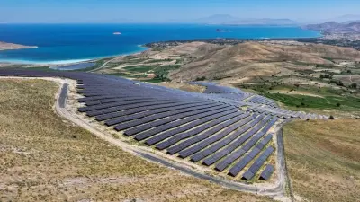 Modern rüzgar türbinleri ve güneş panelleriyle dolu bir enerji çiftliği gün batımında