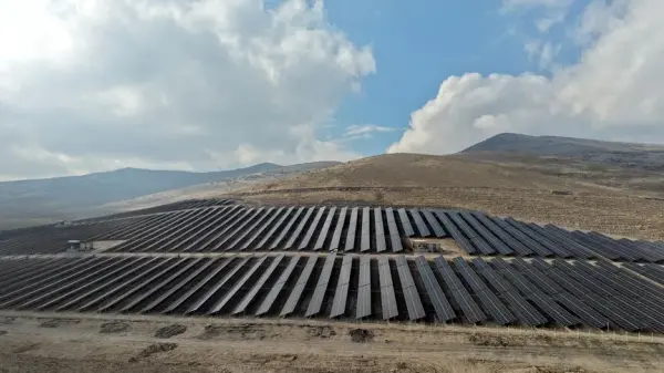 Türkiye'deki bir güneş enerjisi santralinin geniş açılı görünümü, panellerin güneş ışığı altında parladığı bir manzara.