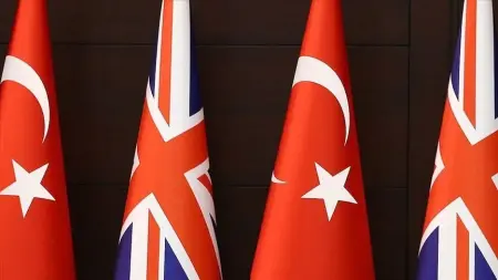 Türkiye ve İngiltere bayrakları önünde tokalaşan yetkililer